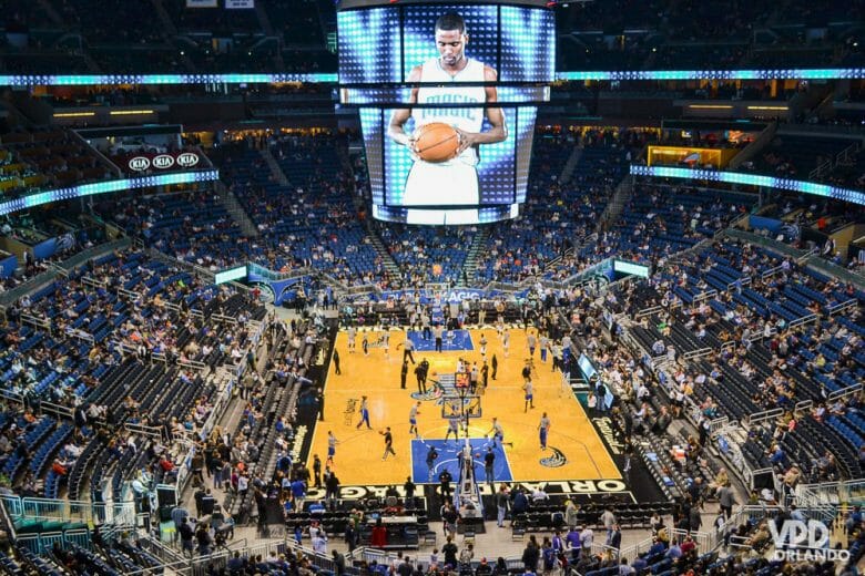 Fevereiro é um ótimo mês para curtir um jogo da NBA em Orlando. Foto do Amway Center durante um jogo da NBA. É possível ver a quadra, os jogadores e as arquibancadas. 