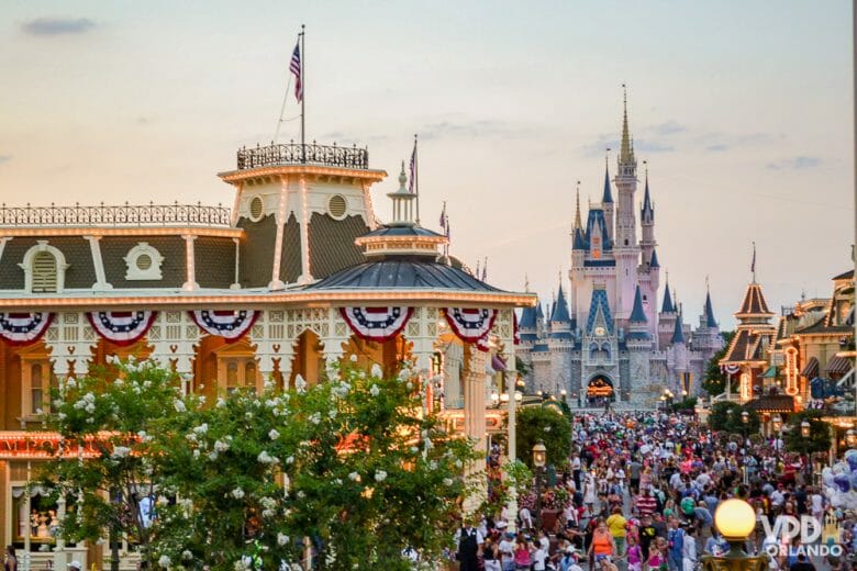 Perto do feriado de fevereiro os parques ficam mais cheios. Foto da Main Street do Magic Kingdom ao entardecer, com muitos visitantes e o castelo da Cinderela ao fundo. 