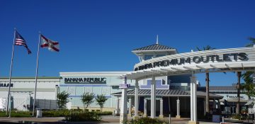 Foto do exterior do Premium Outlet de Tampa, todo pintado de branco e com o céu bem azul ao fundo