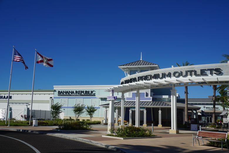 Foto do exterior do Premium Outlet de Tampa, todo pintado de branco e com o céu bem azul ao fundo 