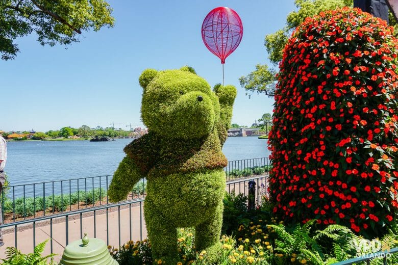 Em março começa o Flower & Garden Festival no Epcot. Foto de uma topiária do Pooh no Epcot, com o lago ao fundo e uma árvore florida ao lado. 