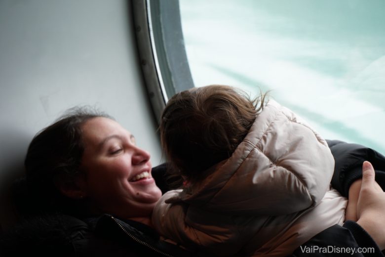 Imagem da Re com sua filha em uma janela do navio Disney Wonder, durante o dia para ver geleiras.