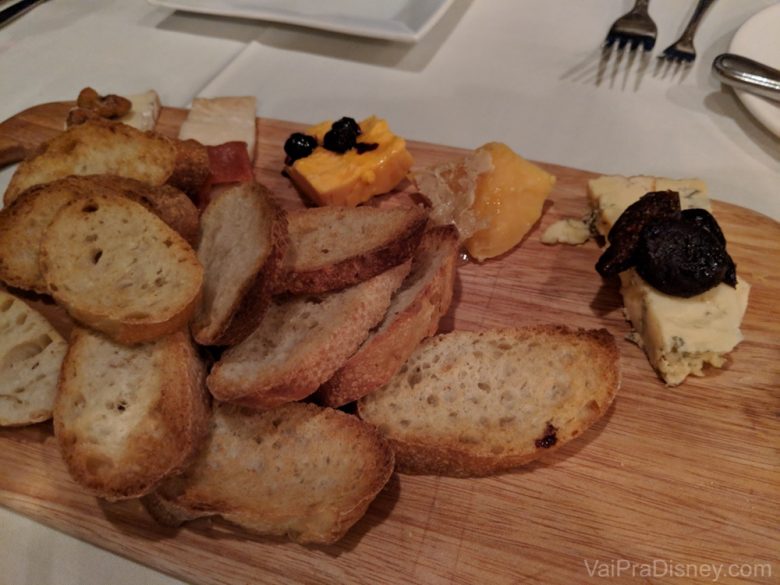 Foto da tábua de queijos do restaurante, com pãezinhos acompanhando 