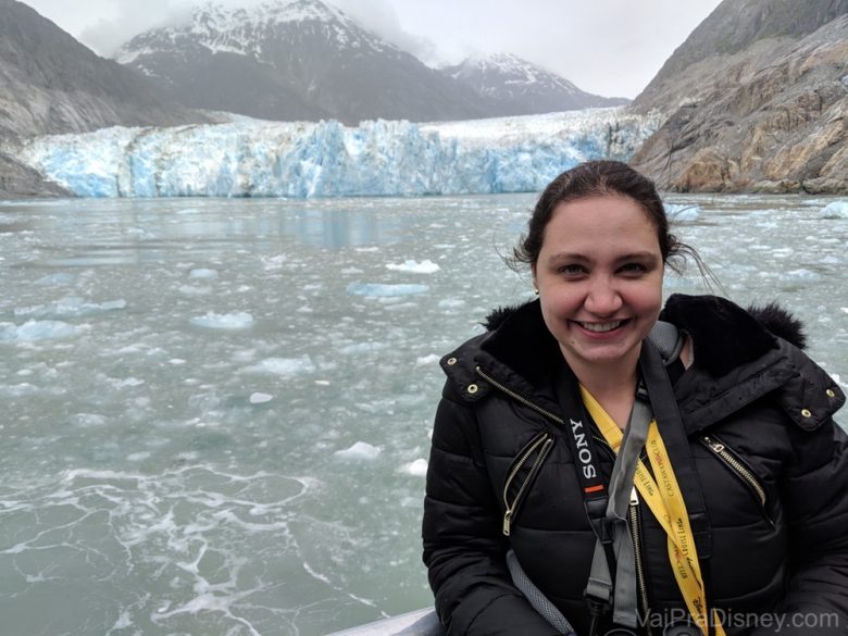 Foto da Renata sorrindo com o mar e as geleiras ao fundo 