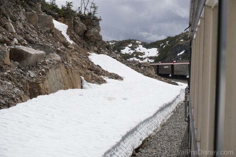 Foto da neve na estrada de ferro na montanha, com o trem passando 