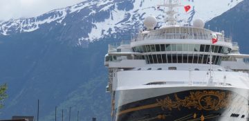 Foto do navio Disney Wonder parado em Skagway, com as montanhas com picos nevados ao fundo