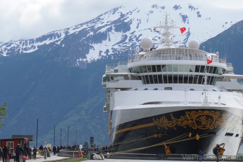 Foto do navio Disney Wonder parado em Skagway, com as montanhas com picos nevados ao fundo 