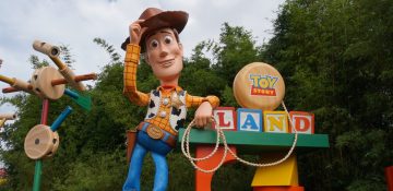 Foto do boneco gigante do Woody na Toy Story Land do Hollywood Studios, com os brinquedos que compõem o cenário ao seu lado.