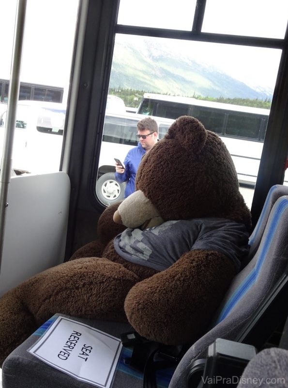 Foto de um urso de pelúcia gigante no assento do ônibus que fazia o passeio Yukon Discovery Tour 