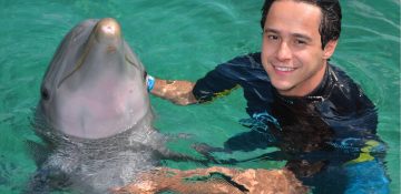 Foto do Henrique com o golfinho durante o cruzeiro da Disney, no Atlantis das Bahamas