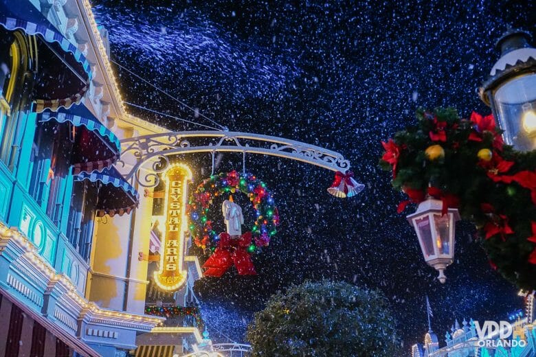Foto da decoração de Natal da Main Street, com guirlandas e neve de mentirinha caindo.
