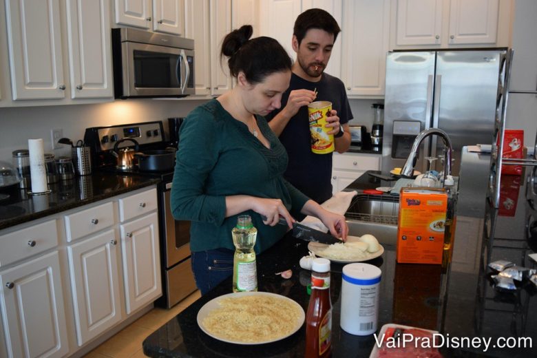 Foto da Renata e do Felipe cozinhando na cozinha de uma casa alugada. É outra opção boa para quem tem criança difícil para comer 