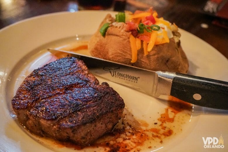 Saber como pedir o ponto da carne do jeito que você gosta em inglês é bem útil. Foto da carne no prato, com a faca que identifica o restaurante (está escrito Longhorn) 