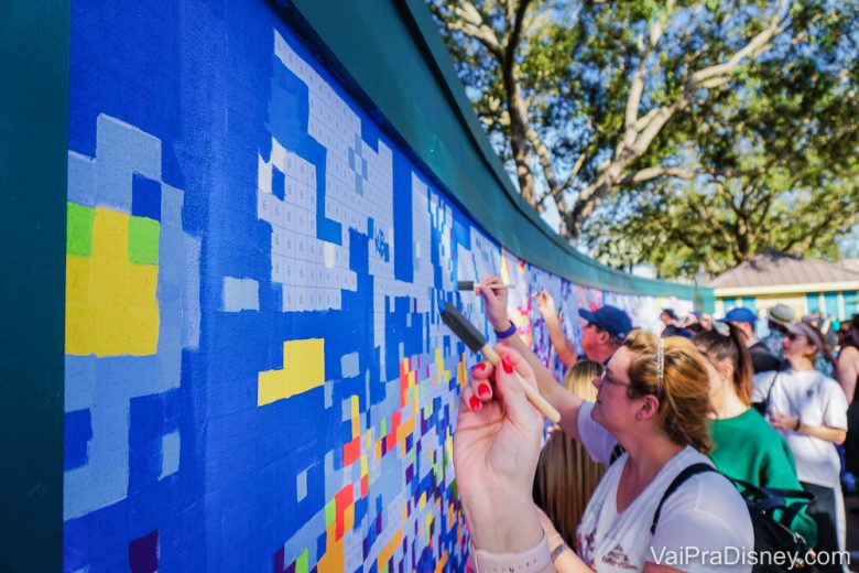 Pessoas pintando o mural com várias cores no Festival of the Arts do Epcot