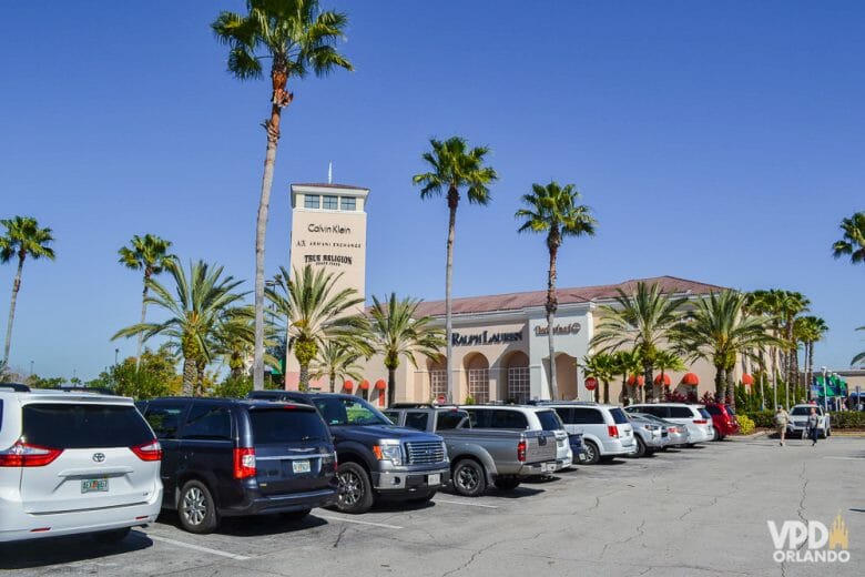 Outlet é sempre bom, mas no feriado em janeiro tem mais desconto ainda! Imagem do estacionamento do Premium Outlet em Orlando, com carros enfileirados e o céu azul ao fundo. 