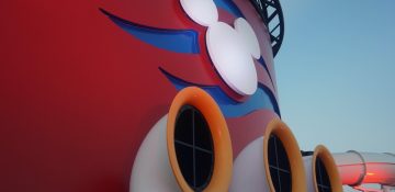 Foto de um detalhe do navio da Disney Cruise Line com o Mickey em branco e o fundo pintado de azul e vermelho.