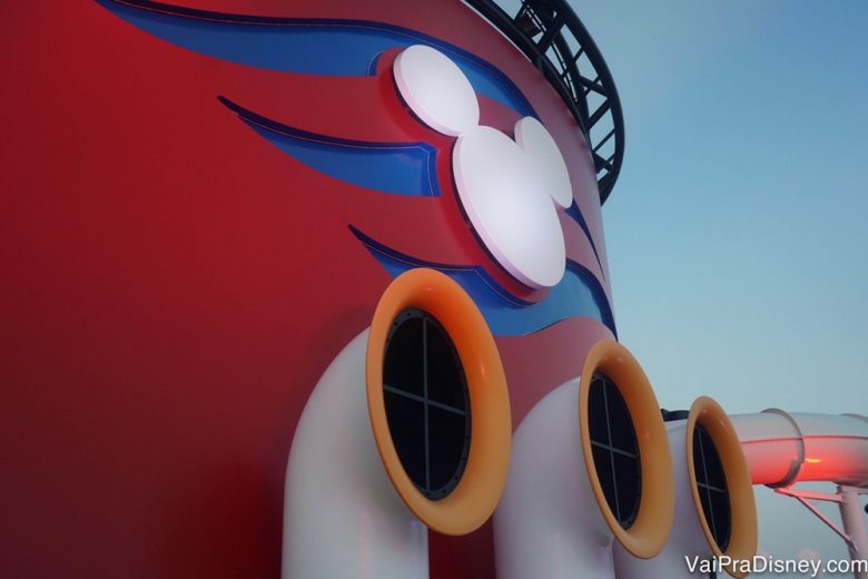 De todo jeito, se você está indo em um cruzeiro, pode ficar feliz! Pode ficar muuuuito feliz! Não tem como não ser incrível! Foto de um detalhe do navio da Disney Cruise Line com o Mickey em branco e o fundo pintado de azul e vermelho. 