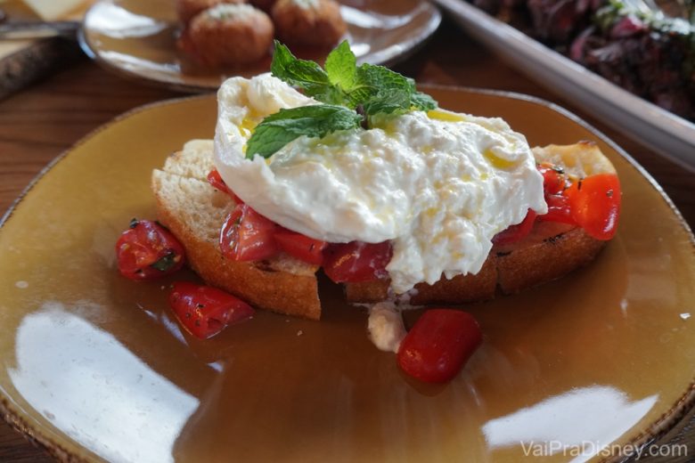 A burrata com tomatinho em cima do pão.  