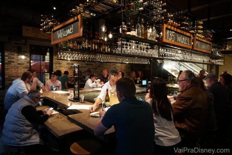 Foto do bar no interior do restaurante, com diversos visitantes sentados 