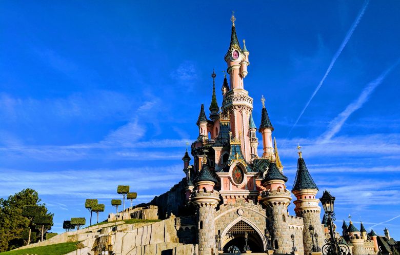 Foto do castelo da Bela Adormecida, na Disneyland de Paris, com o céu azul ao fundo.