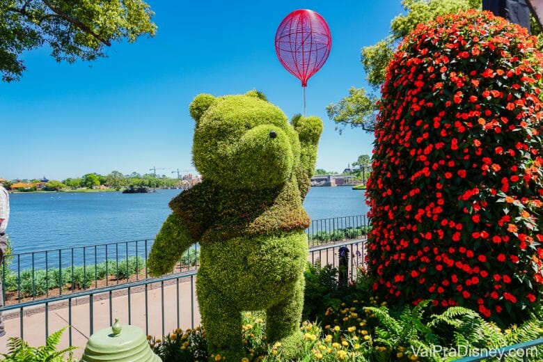 Foto da topiária do Pooh com um balão durante o Flower & Garden, com o lago do Epcot ao fundo 