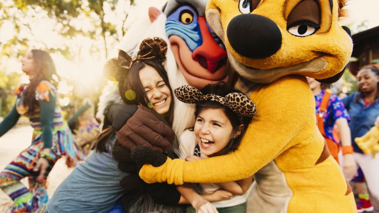 Foto dos visitantes abraçando o Rafiki e o Timão durante o Harambe at Night 