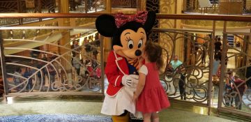 Foto da Minnie recebendo um beijo de uma criança durante um dos cruzeiros da Disney