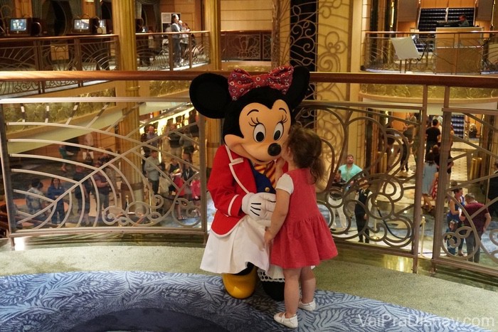 Foto da Minnie recebendo um beijo de uma criança durante um dos cruzeiros da Disney 