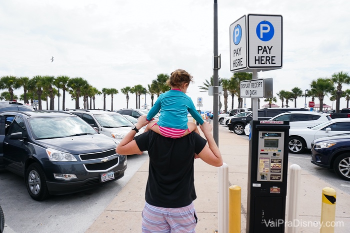 Foto do Felipe com a Júlia nos ombros no estacionamento da praia 