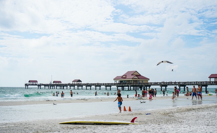 Foto da praia de Clearwater, com gaivotas voando e um píer ao fundo 