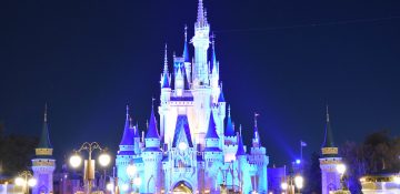 Foto do castelo da Cinderela no Magic Kingdom, iluminado em azul com o céu escuro ao fundo