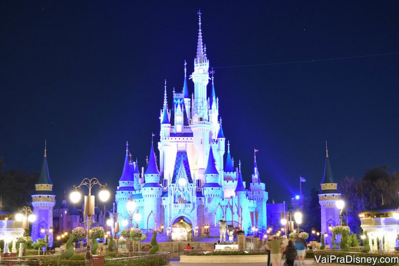 Foto do castelo da Cinderela no Magic Kingdom, iluminado em azul com o céu noturno atrás e todas as luzes da Main Street já acesas 