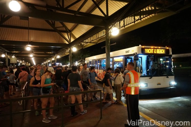 Foto do ônibus do complexo da Disney, indo buscar visitantes que aguardam em fila. 