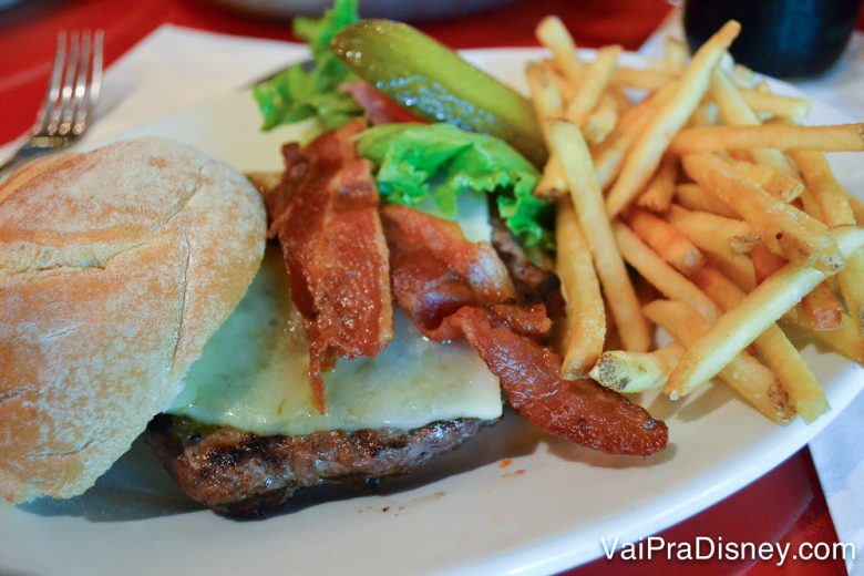 Foto do hambúrguer do restaurante, com bacon e batatas fritas ao lado 