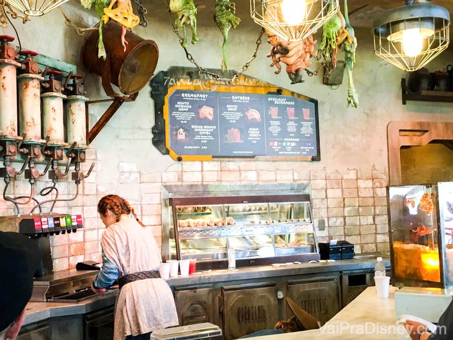 Foto de uma lanchonete em Star Wars Galaxy's Edge, com uma decoração temática e uma atendente com roupas temáticas 