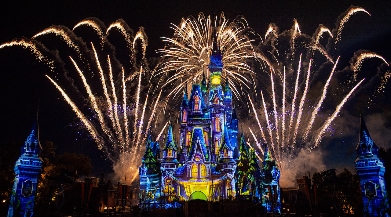 Imagem do show de fogos da Festa de Halloween da Disney, com o castelo da Cinderela iluminado por projeções coloridas. 