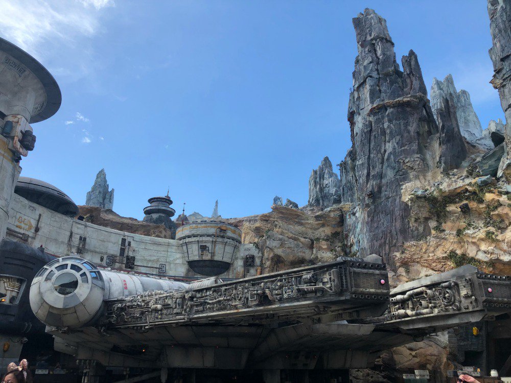 Foto da Millenium Falcon com as montanhas de Batuu e o céu azul ao fundo na Star Wars: Galaxy's Edge