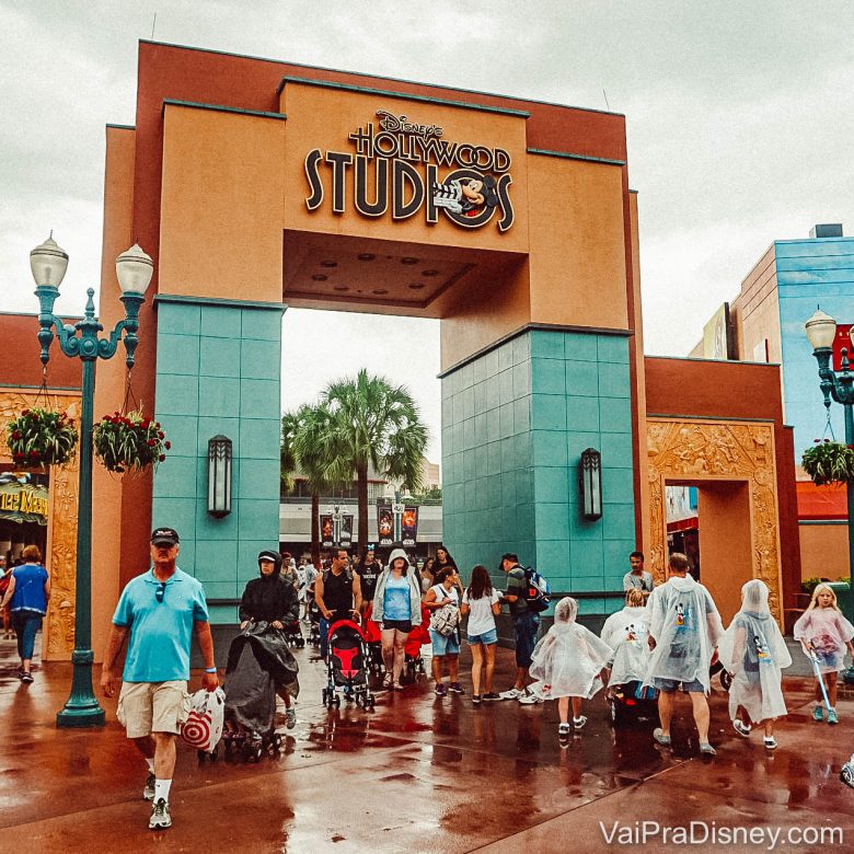 Foto do portal do Hollywood Studios em um dia de chuva, com diversos visitantes passando com capas de chuva 