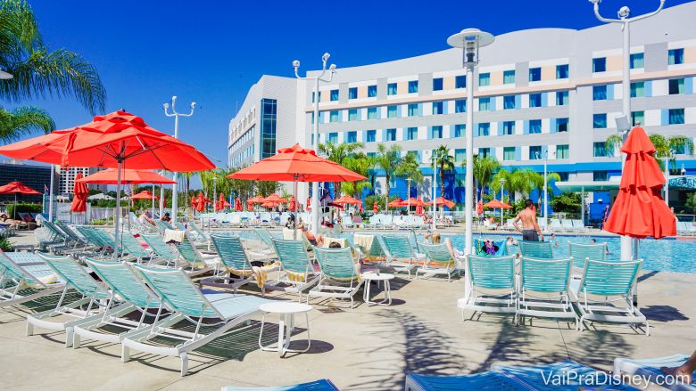 Foto da piscina do Endless Summer, um dos hotéis da Universal em Orlando. As cadeiras de praia são azuis e os guarda-sóis são alarajados. 