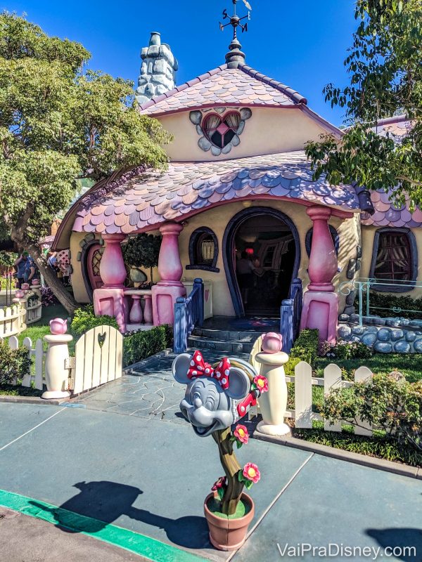 Foto da casa da Minnie na Toontown da Disney California, pintada de rosa e lilás e com um vaso de flores e uma cabeça de Minnie na frente 