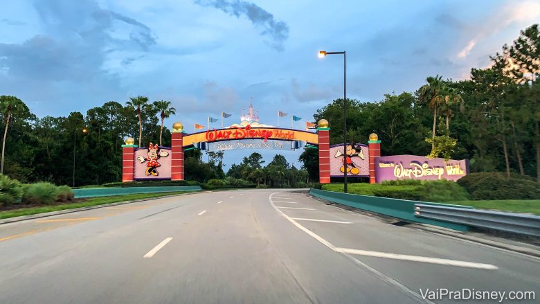 Foto do portal de entrada do complexo da Disney em Orlando, com o castelo no centro da placa que diz Walt Disney World e o Mickey e a Minnie de cada um dos lados 