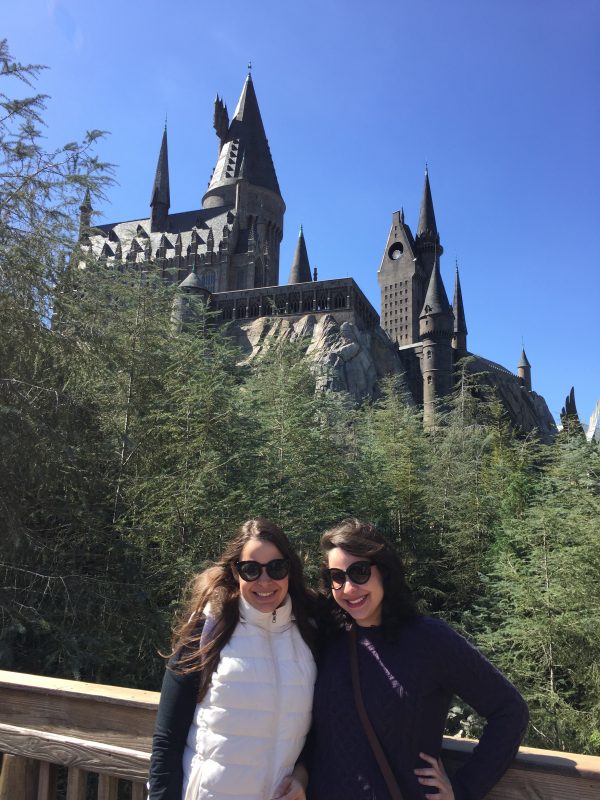 Bia e Julinha: quem é quem? Valeeeendo! Foto da Bia e da Julia, da equipe do VPD, em frente ao castelo de Hogwarts na Universal em um dia de céu azul 