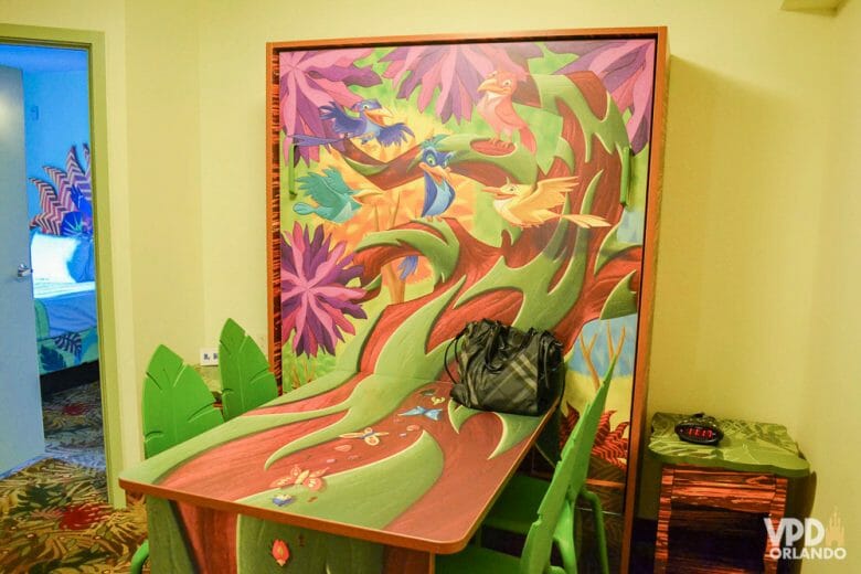 Mesa que vira cama no quarto do Rei Leão, na versão mesa mesmo, fechada. A mesa é decorada com os pássaros do filme em uma árvore marrom e verde. 