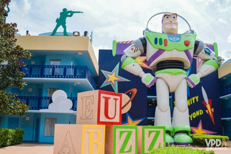 Boneco do Buzz Lighyear em frente a um prédio azul do All-Star Movies. Blocos com as letras BUZZ estão ao lado dele. 