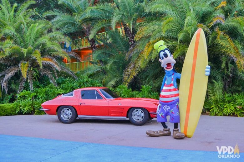 Foto do Pateta com roupas de praia e uma prancha de surf, ao lado de um carro antigo, na decoração do hotel Pop Century