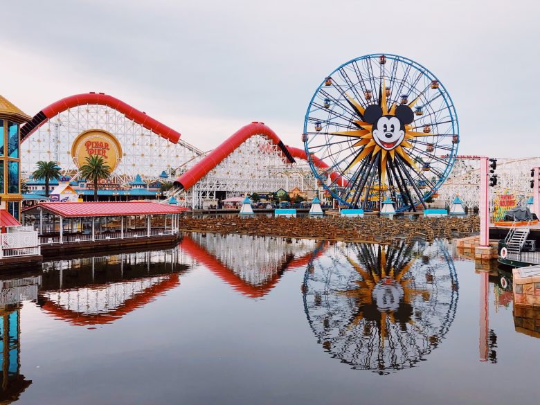 Foto do parque Disney's California Adventure, na Disneyland, mostrando a roda gigante com o rosto do Mickey e o lago que fica em frente a ela. 