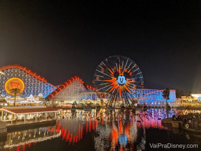 Foto da roda gigante com o Mickey no centro e do Pixar Pier todo iluminado à noite na Disneyland California 