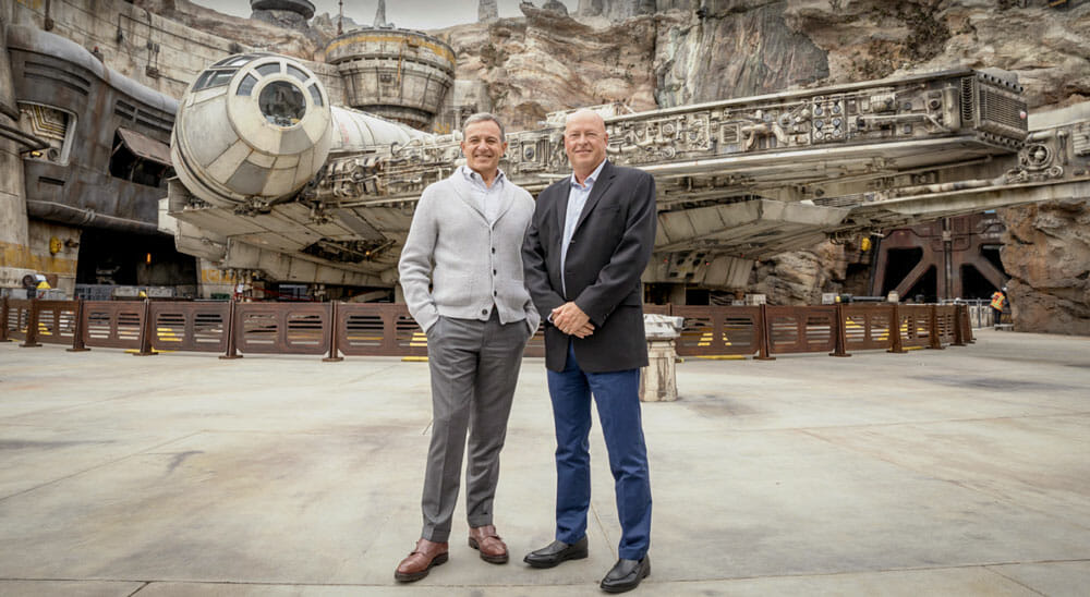 Foto de Bob Iger e Bob Chapek na abertura da Star Wars: Galaxy's Edge, sorrindo em frente à Millenium Falcon.