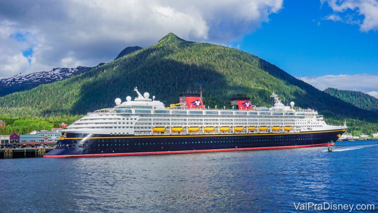 Foto do navio de cruzeiro da Disney em alto mar, com montanhas ao fundo. Os cruzeiros também precisaram se adaptar para evitar a transmissão do coronavírus 