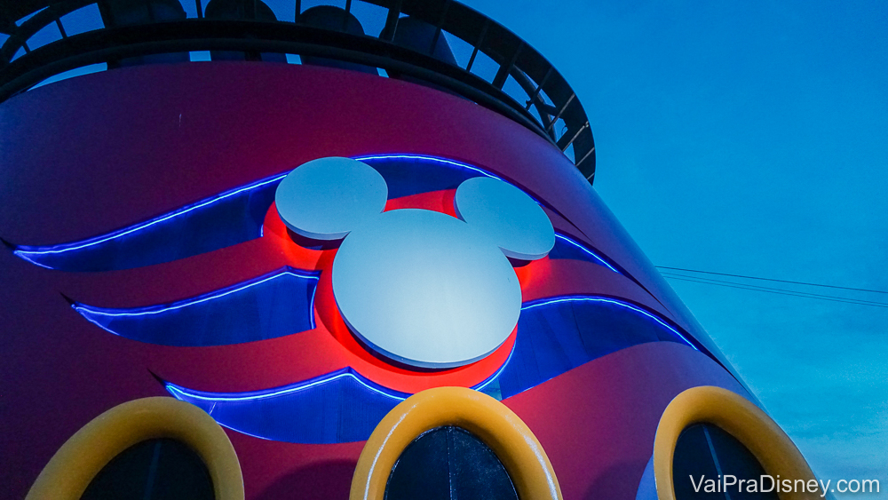 Foto do Mickey que decora parte do navio da frota da Disney Cruise Line. O símbolo é branco e o fundo é listrado em vermelho e azul.